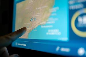 Close up image passenger on the plane by touching the LCD entertainment screen. focus on the screen photo