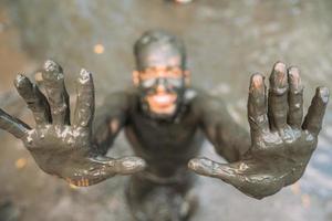 smiling young latin american man doing green clay treatment. focus on hands photo