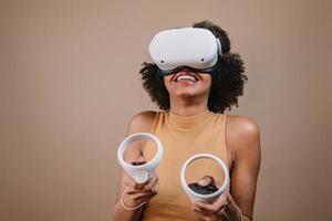 Latin young woman standing with VR goggles and keep joysticks or finger as a gun. photo