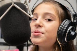 Girl singing in studio microphone. Condenser microphone. Child singer. photo