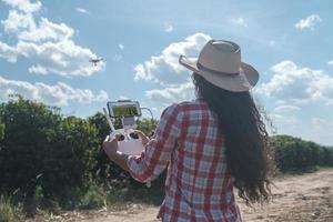 Young woman farmer analyzing a coffee plantation through a drone. Farmer using drone to fly over his coffee plantation. Technology on the farm. photo