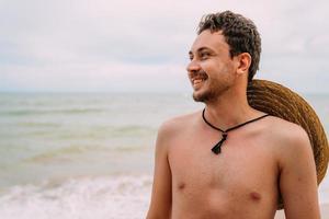 young latin american man on the beach with a hat. smiling man looking at left photo