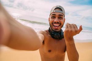 Friendly young Latin American man inviting to come to Brazil, confident and smiling making a gesture with his hand, being positive and friendly photo