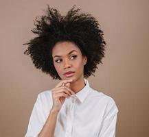 Closeup of a young Latin afro woman thinking. Joy, positive and love. Beautiful african-style hair. Pastel studio background. photo