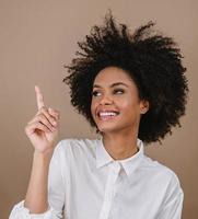 A young Latin girl points to the sides. Advertisement and presentation concept. Pastel background. photo