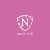 plantilla de diseño de logotipo inicial de letra n. ilustración de escudo floral decorativo de plata de lujo. aislado sobre fondo de color rosa. Adecuado para productos de seguros, moda y belleza. vector