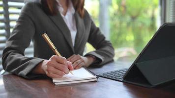 mano della donna di affari che lavora con il nuovo computer moderno e che scrive sul diagramma di strategia del blocco note come concetto video