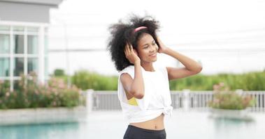 African woman in sportswear wearing headphones dancing at swimming pool background video