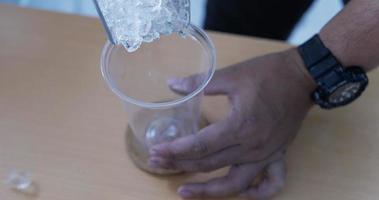 verter cubo de hielo en un vaso de plástico. video