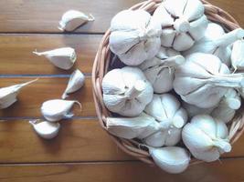 garlic bulb on wicker basket on wooden background photo