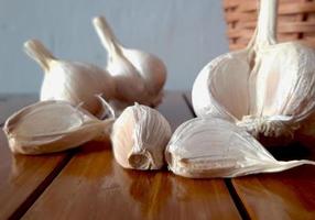 Fresh garlic in a wicker basket on a wooden table photo