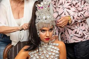 Young girl in bright colorful carnival costume preparation. Beautiful brunette preparing for Brazilian carnaval. photo