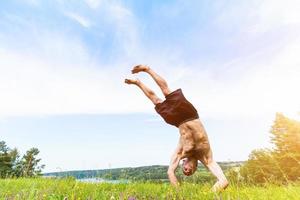 Young man doing a handstand on a filed. photo