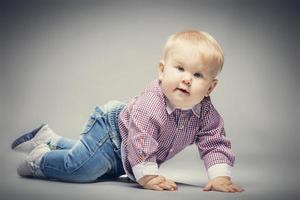 Little blond baby boy crawling on the ground. photo