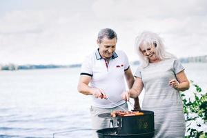 Senior couple preparing sausages on the barbeque photo