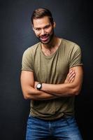 hombre guapo sonriendo, de pie confiado con los brazos cruzados foto