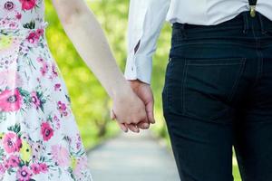 Young couple in love holding hands in summer park. Dating photo