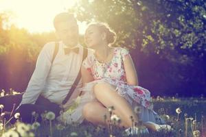 Romantic couple in love flirting on grass in sunny park. Vintage photo