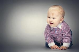 Smiling little boy crawling on the ground. photo