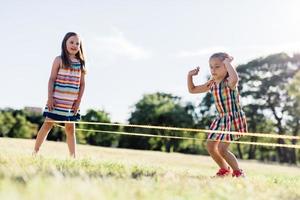 Two girls playing Chinese jumping rope in the park. photo