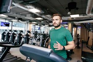 Man in his 30s running on a treadmill. photo