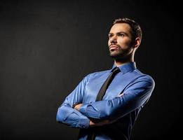 Handsome young businessman standing confident on black photo