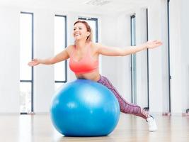 mujer alegre entrenando con fitball en el gimnasio. foto