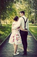 Young couple embrace while standing on wooden path photo
