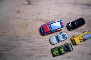 varios autos de juguete alineados ordenadamente en la madera. coches de juguete fotografiados desde arriba. algunos coches de juguete en la parte inferior derecha. foto