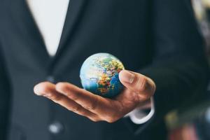 Business man holding earth globe model in hand and - Business global and travel around the world or save the world concept photo