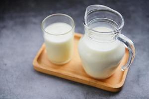 leche fresca natural en una jarra de vidrio en una bandeja de madera - concepto de leche para el desayuno foto