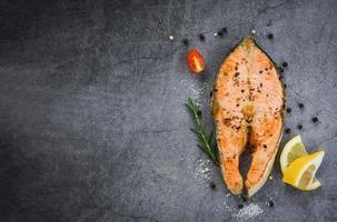 Salmon fish fillet steak seafood Grilled salmon steak with herbs and spices rosemary lemon on dark background photo