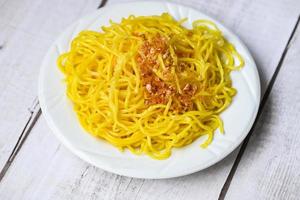 yellow noodles on white plate and wooden background , instant noodles yellow noodles rice vermicelli food with fried garlic photo
