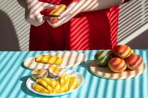 manos femeninas cortan mango y fruta de la pasión, desayuno de frutas foto