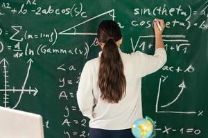 Girl writes mathematical examples on the school board. solves a geometry problem. photo