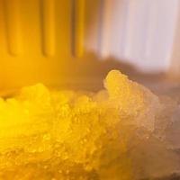 The freezer compartment of the refrigerator is heavily frozen with an orange glow. photo