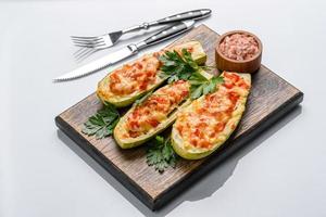 Baked stuffed zucchini boats with minced chicken mushrooms and vegetables with cheese photo