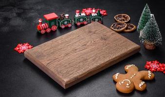Christmas homemade gingerbread cookies, spices and cutting board on dark background photo