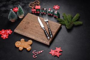 Christmas homemade gingerbread cookies, spices and cutting board on dark background photo