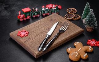 Christmas homemade gingerbread cookies, spices and cutting board on dark background photo