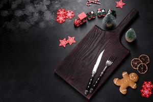 Christmas homemade gingerbread cookies, spices and cutting board on dark background photo