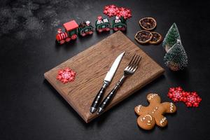 Christmas homemade gingerbread cookies, spices and cutting board on dark background photo