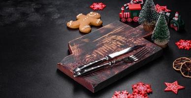 Christmas homemade gingerbread cookies, spices and cutting board on dark background photo