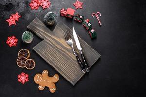 Christmas homemade gingerbread cookies, spices and cutting board on dark background photo