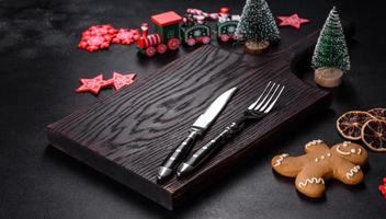 Christmas homemade gingerbread cookies, spices and cutting board on dark background photo