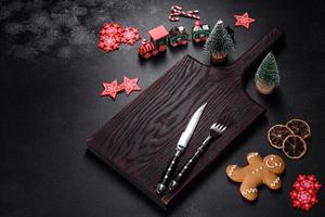 Christmas homemade gingerbread cookies, spices and cutting board on dark background photo