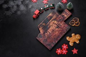 Christmas homemade gingerbread cookies, spices and cutting board on dark background photo
