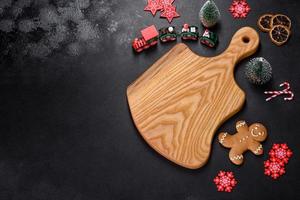 Christmas homemade gingerbread cookies, spices and cutting board on dark background photo