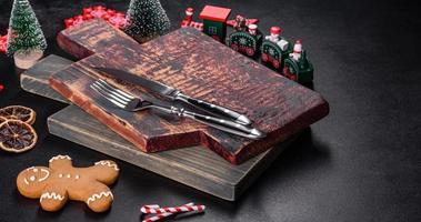 Christmas homemade gingerbread cookies, spices and cutting board on dark background photo