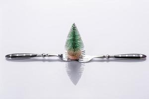 A small Christmas tree decoration on two forks on a white background photo